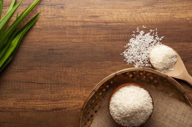 Yasemin pirinç bir kase ve tahta kaşıkla üstten görünüm üzerinde kırmızı çiçekli koyu ahşap masa.