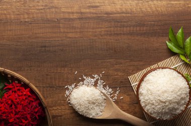 Yasemin pirinç bir kase ve tahta kaşıkla üstten görünüm üzerinde kırmızı çiçekli koyu ahşap masa.