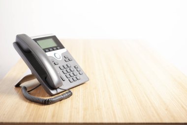 Hafif ahşap zemin, bekleyen telefon konuşması üzerinde önden görünüm dijital telefon. İş iletişim kavramları