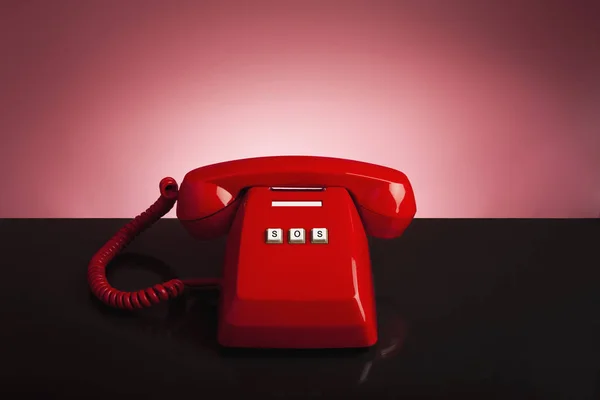 Emergency call 911 on the telephone, red old vintage telephone on black background and desk, emergency call concept.