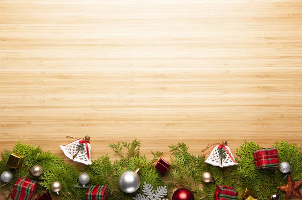 Top view of Christmas background, template with decorations of balls, gift boxes, white bells on fir tree on with wooden background with copy space, ornaments for new year greetings.