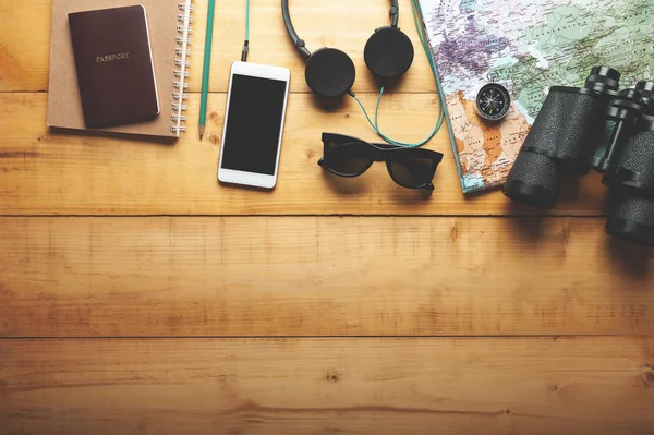 Top view of world map, headphone, binocular, smartphone and pass