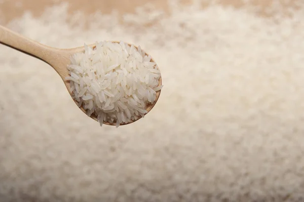 Vista de cerca del arroz en una cuchara de madera sobre fondo de madera — Foto de Stock