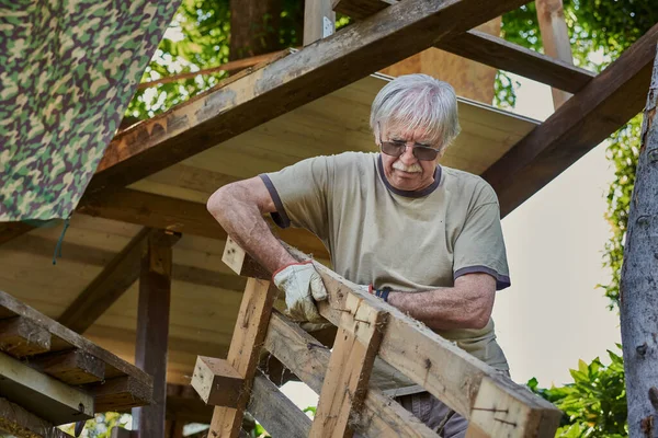 Активний старший чоловік на пенсії працює на задньому дворі, посміхаючись Стокове Фото
