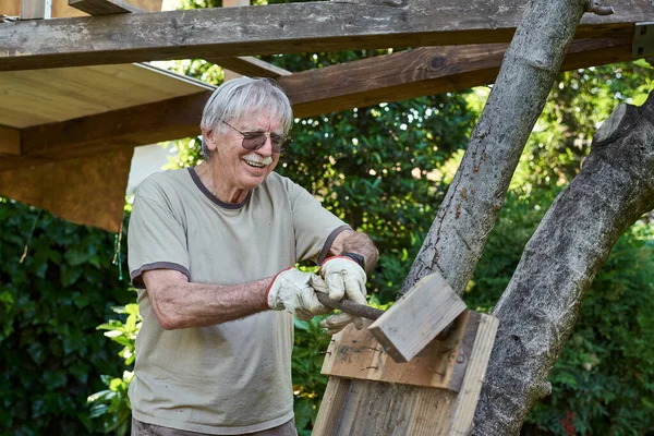 Активний старший чоловік на пенсії працює на задньому дворі, посміхаючись — стокове фото