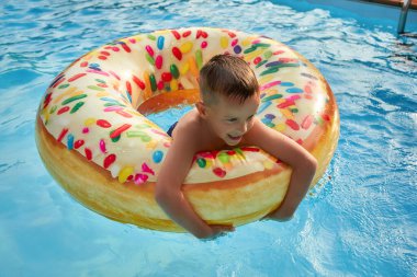 Şişirilebilir renkli yüzükte yüzme havuzunda 5 yaşında bir çocuk.