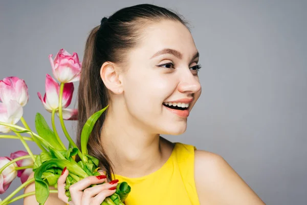 黄色のドレスで幸せな若い女の子喜ぶ春の休日、手でピンクの花の花束を保持 — ストック写真