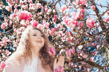 kıvırcık saçlı gülen genç kadın yanındaki parkta pembe bir kokulu Manolya poz