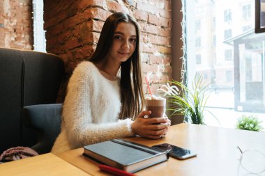 kafede otururken, güzel kokulu kapuçino içiyor ve kameraya bakıyor güzel bayanı serbest meslek