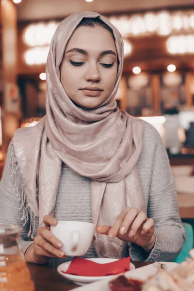 Gyönyörű fiatal Arab nő, a fejkendő a fején egy hangulatos szép kávézóban ebédel — Stock Fotó