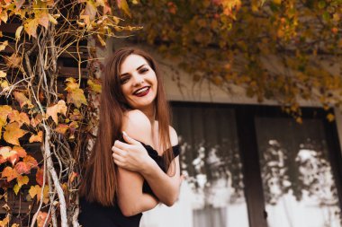 onu bahçede poz ve gülümseyerek kameraya bakarak uzun saçlı lüks zarif kadın