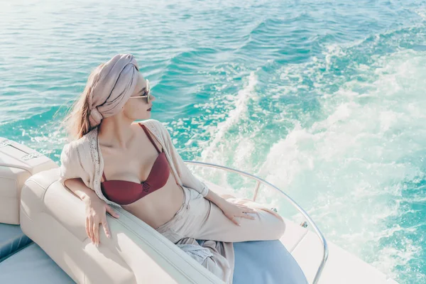 Una chica elegante de lujo con un pañuelo en la cabeza en sus gafas de sol se relaja en su yate blanco, unas vacaciones tan esperadas —  Fotos de Stock