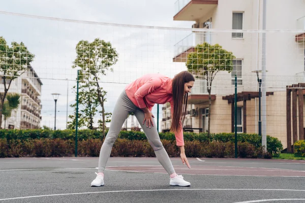 Activa chica delgada amasar los músculos antes de un entrenamiento difícil en el campo de deportes — Foto de Stock