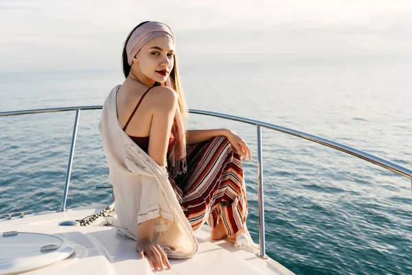 A luxurious rich woman sits on her white yacht, sails across the Caribbean and smiles — Stock Photo, Image