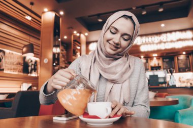 güzel kokulu çay içme güzel Arap kız rahat bir oryantal kafede oturan ve lezzetli yemek bir başörtüsü ile