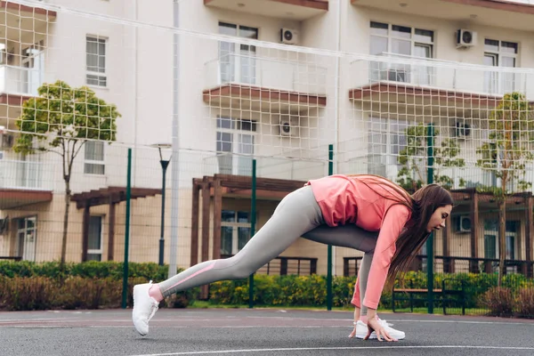 Atletische jong meisje warming-up en stretching voor opleiding op het sportveld — Stockfoto