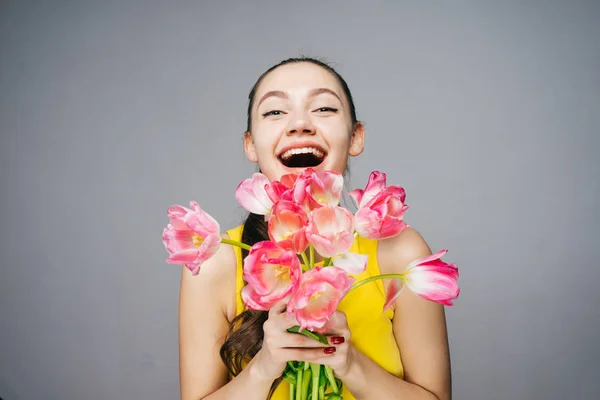 Hermosa chica feliz sosteniendo un ramo de flores rosadas fragantes, disfrutando de la primavera — Foto de Stock
