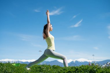 ince etkin kız parkta yeşil çimenlerin üzerinde yoga yapan, derin derin düşünür ve rahatlatır