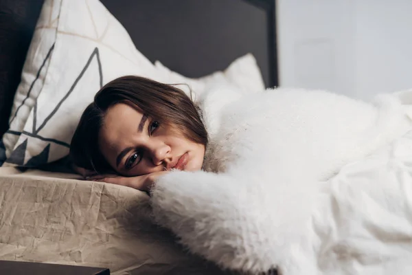 Fată tânără somnoroasă în pijamale albe se află în pat, nu vrea să se ridice — Fotografie, imagine de stoc