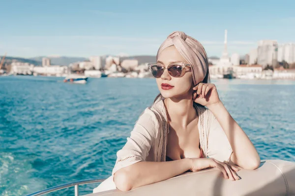 Una mujer rica de lujo en gafas de sol se relaja y descansa en su yate, un viaje por el mar —  Fotos de Stock