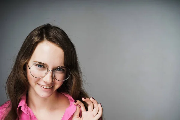 Schöne blauäugige Frau in rosa Hemd und Brille, die lächelt und in die Kamera schaut — Stockfoto