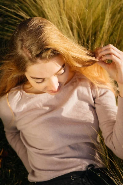 Chica joven rubia acostada en la hierba verde en el sol, sonriendo y descansando — Foto de Stock