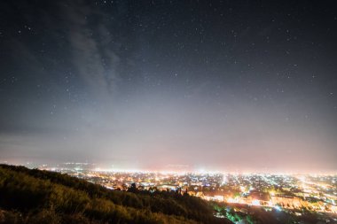 Bir gece yıldızlı gökyüzü, birçok fenerler ve ışıklar altında bir şehir yukarıdan bir görünüm
