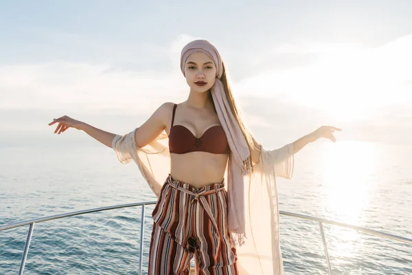 Mujer joven elegante de lujo con pañuelo para la cabeza y ropa de verano elegante posando en un yate blanco, navegando en el mar Caribe —  Fotos de Stock