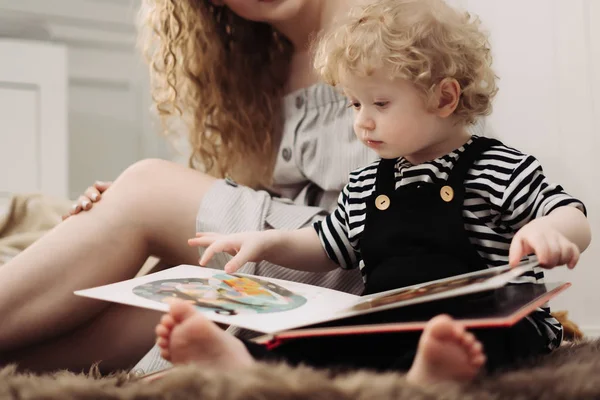 Small curly baby boy sitting on the floor with his mother, learning to read, studying the world — Stock Photo, Image