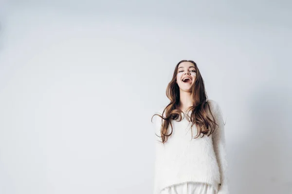 Feliz joven de pelo largo chica en pijama blanco se ríe y se regocija en un nuevo día, dormido — Foto de Stock