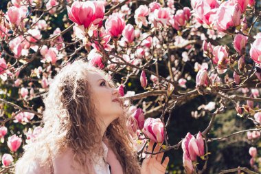 sıcaklık ve bahar parkta güzel kokulu Pembe Manolya çiçek, koklama kıvırcık güzel kadının