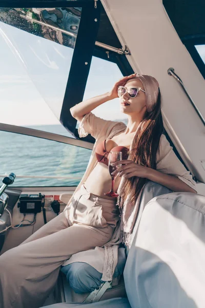 Lüks bir genç kadın güneş gözlüğü zengin bir hayat onun yatta içecekler şampanya sahiptir.