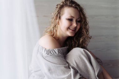 mutlu pencere ve gülüyor tarafından içinde bir kıvırcık genç kadın oturur