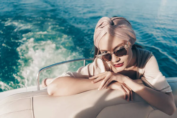 Une fille élégante de luxe avec un foulard et portant des lunettes de soleil repose sur son yacht, navigue vers les îles en vacances — Photo