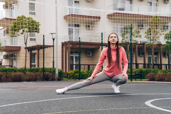 Впевнена сильна дівчина коліна і розтягується на спортивному полі, хоче красиву фігуру — стокове фото
