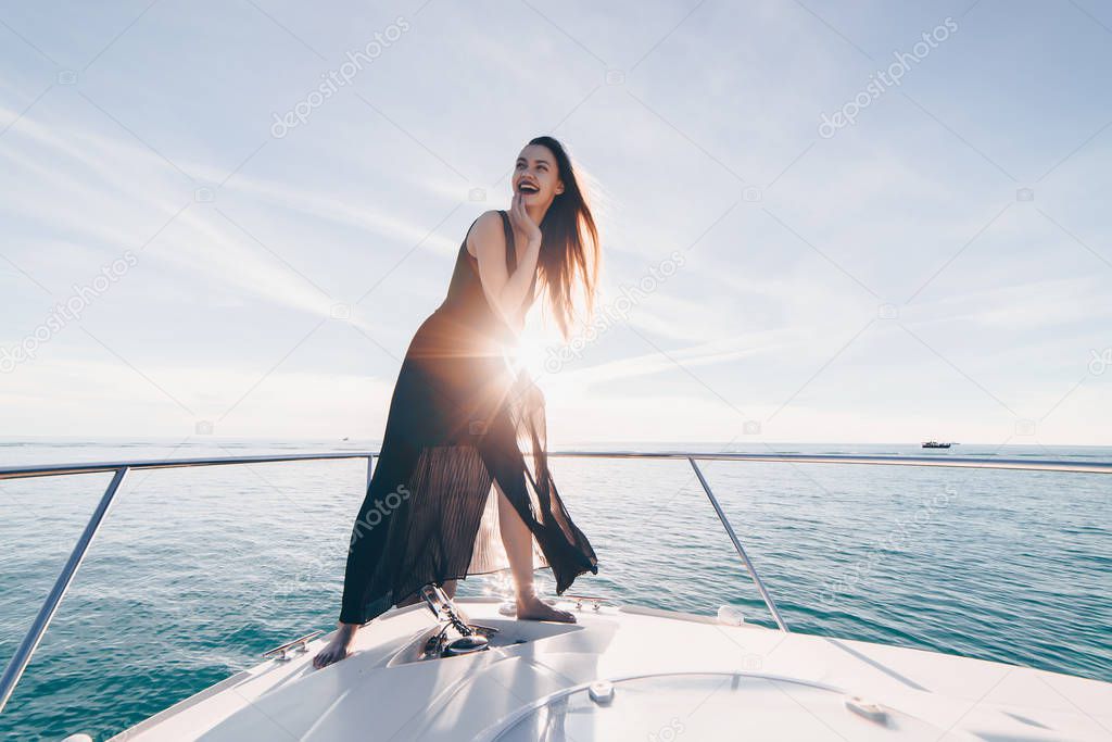 luxurious stylish girl in black clothes posing on her white yacht, sailing on the Caribbean sea