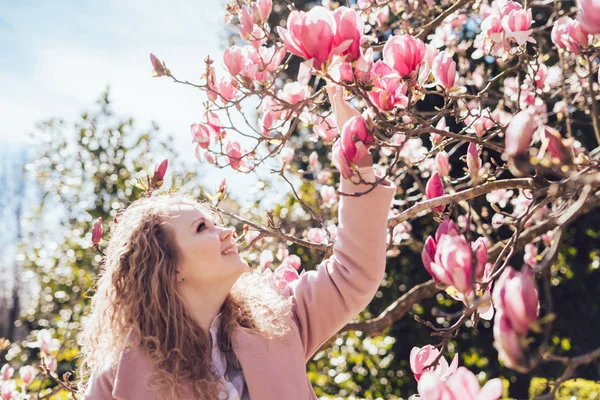 Feliz joven olfateando una fragante magnolia floreciente en el parque, feliz primavera y sol — Foto de Stock