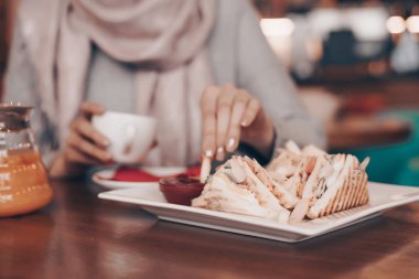 Bir Müslüman kız rahat bir oryantal restoranda oturur ve lezzetli bir yemek, bir sandviç yiyor