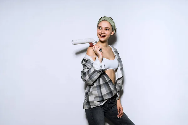 Schattige lachende meisje in een shirt met een roller voor het schilderen van de muren, doen reparaties in het appartement — Stockfoto