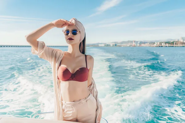 Una joven de lujo en gafas de sol nada en un yate en el mar Caribe, mira a la distancia —  Fotos de Stock