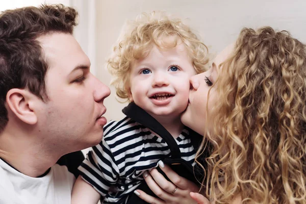 Familia joven y amigable, padres jóvenes, mamá y papá mantienen a su pequeño hijo en sus brazos — Foto de Stock