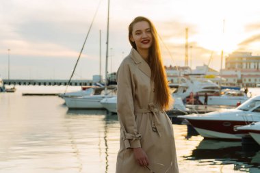 gün batımında liman içinde poz bej moda ceket lüks uzun saçlı Genç kız