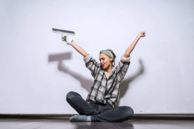 ekose gömlekli mutlu genç kız evinde onarım yapıyor bir spatula tutarak yere, oturma