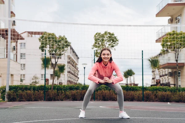Leuke actieve meisje traint en oefeningen doet op grond van een outdoor sporten, wil om gewicht te verliezen — Stockfoto