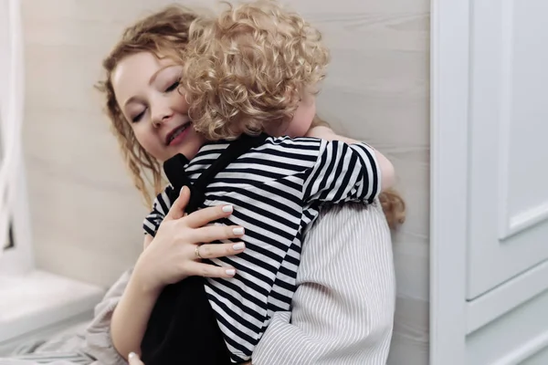 Piękny przetargu młoda matka przytulanie swojego synka kręconych włosach, uśmiech, przyjazne rodzinie — Zdjęcie stockowe
