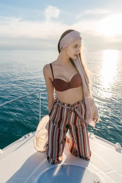 Magabiztos fiatal lány pózol a vele fehér jacht a nap, elegáns nyári ruha élvezi az ünnepek — Stock Fotó
