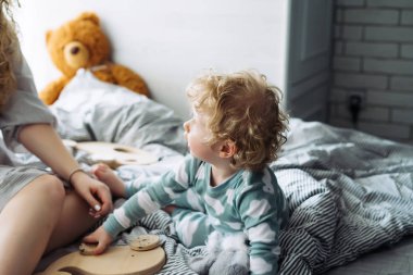 kıvırcık küçük bebek yatakta annesiyle birlikte oynayan oturma