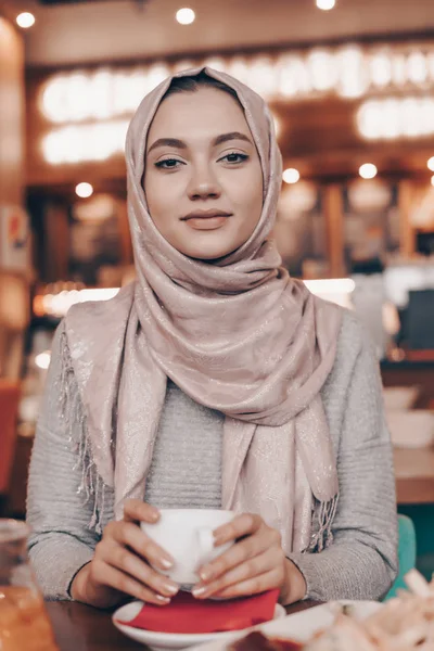 Vonzó Arab lány hidzsáb gyönyörű kávézóban illatos kávé italok, úgy néz ki, a kamera — Stock Fotó