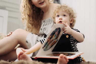 dostu aile, iyi bir genç anne yere küçük kıvırcık çocuk çocuk oğlu, oyun yanında oturur