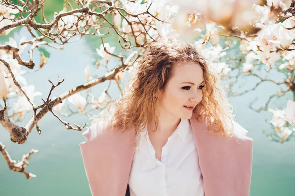 Happy beautiful young woman enjoys relaxing in a park by the pond in the sun, smiling — Stock Photo, Image